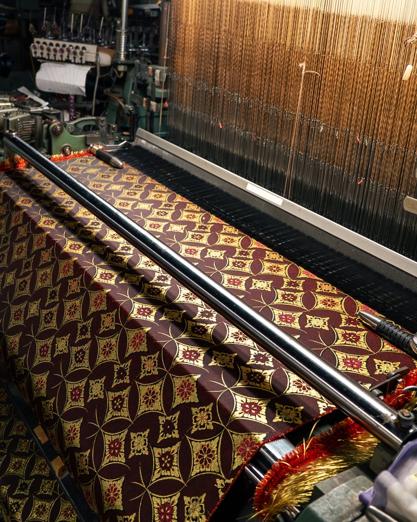 A Kyoto loom weaving Kyo-ori jacquard in deep crimson and gold.